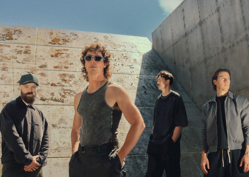Band Don Broco with grey wall behind them and skyx